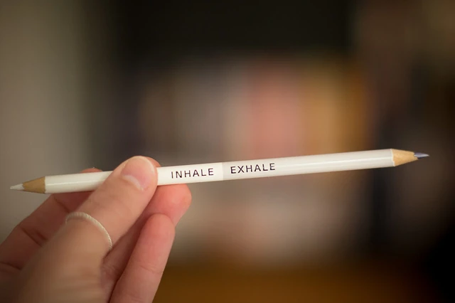 Hand holding a pencil labelled “INHALE EXHALE”.