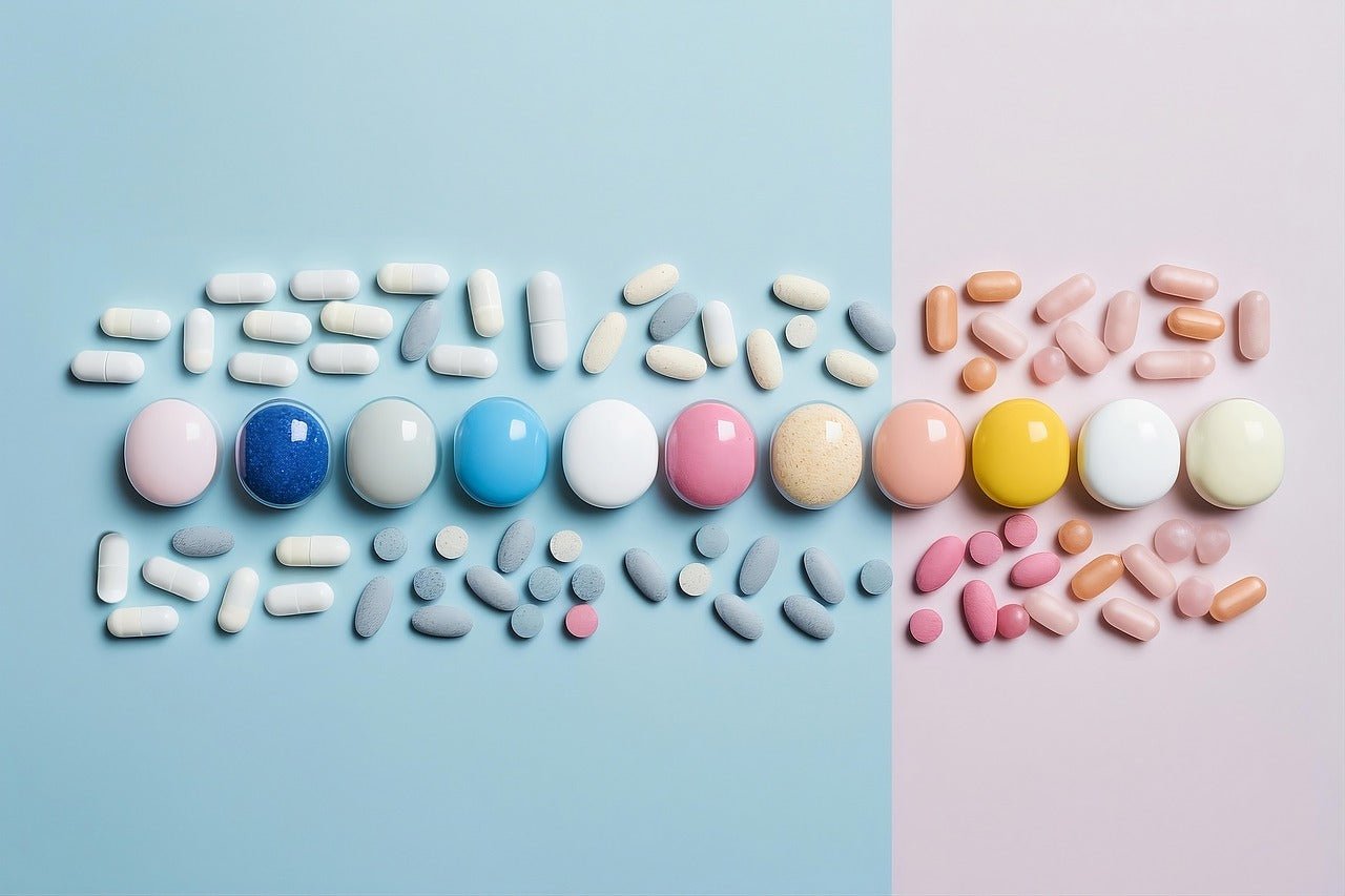 Colourful tablets and capsules arranged on blue and pink backgrounds.